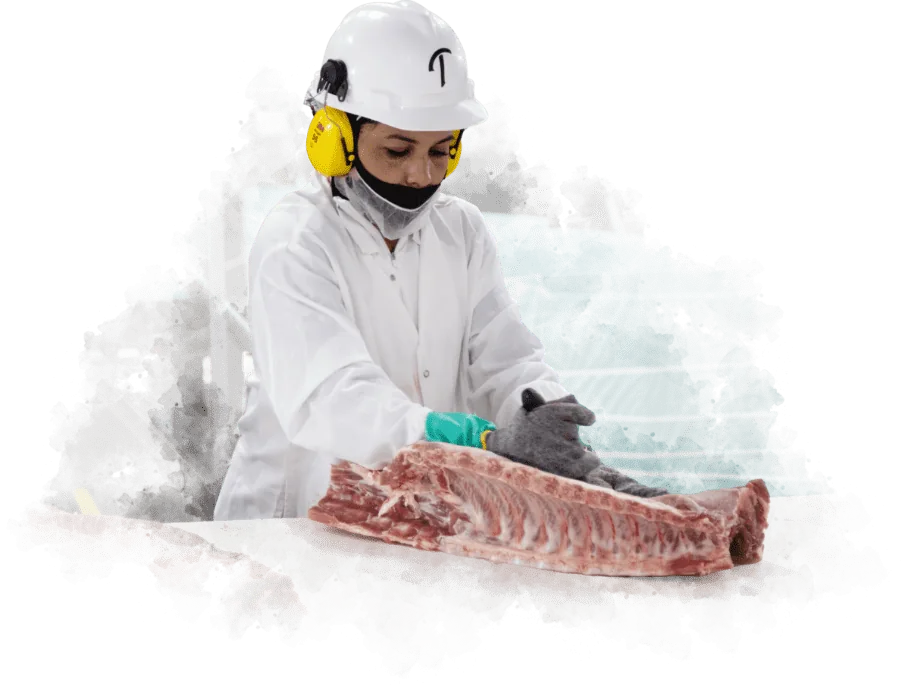 Triumph Foods team member trimming pork